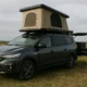 acia Sandman camping-car aménagé avec tente de toit, stationné sur un champ