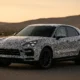 Prototype SUV Porsche camouflé sur route au coucher du soleil
