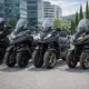 Alignement de quatre scooters à trois roues sur route, pour un comparatif des meilleurs modèles